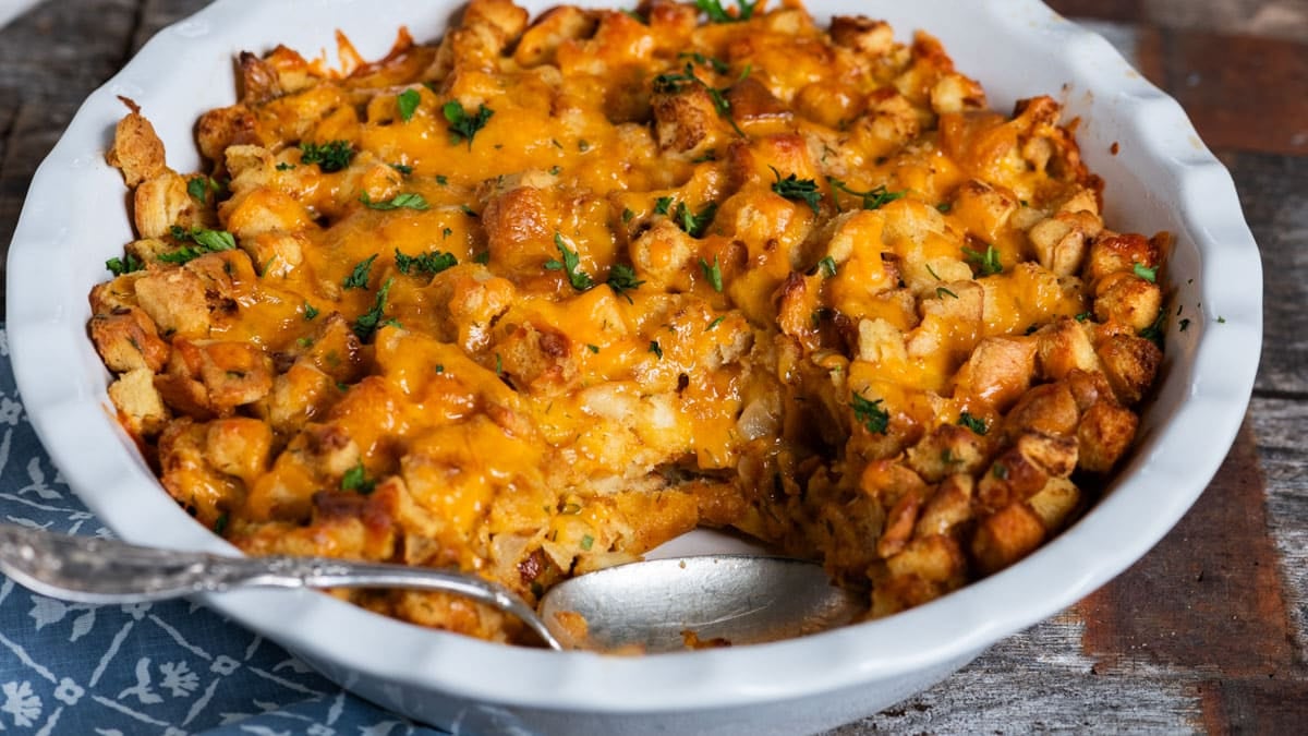 cheesy stuffing in a baking dish with a spoon
