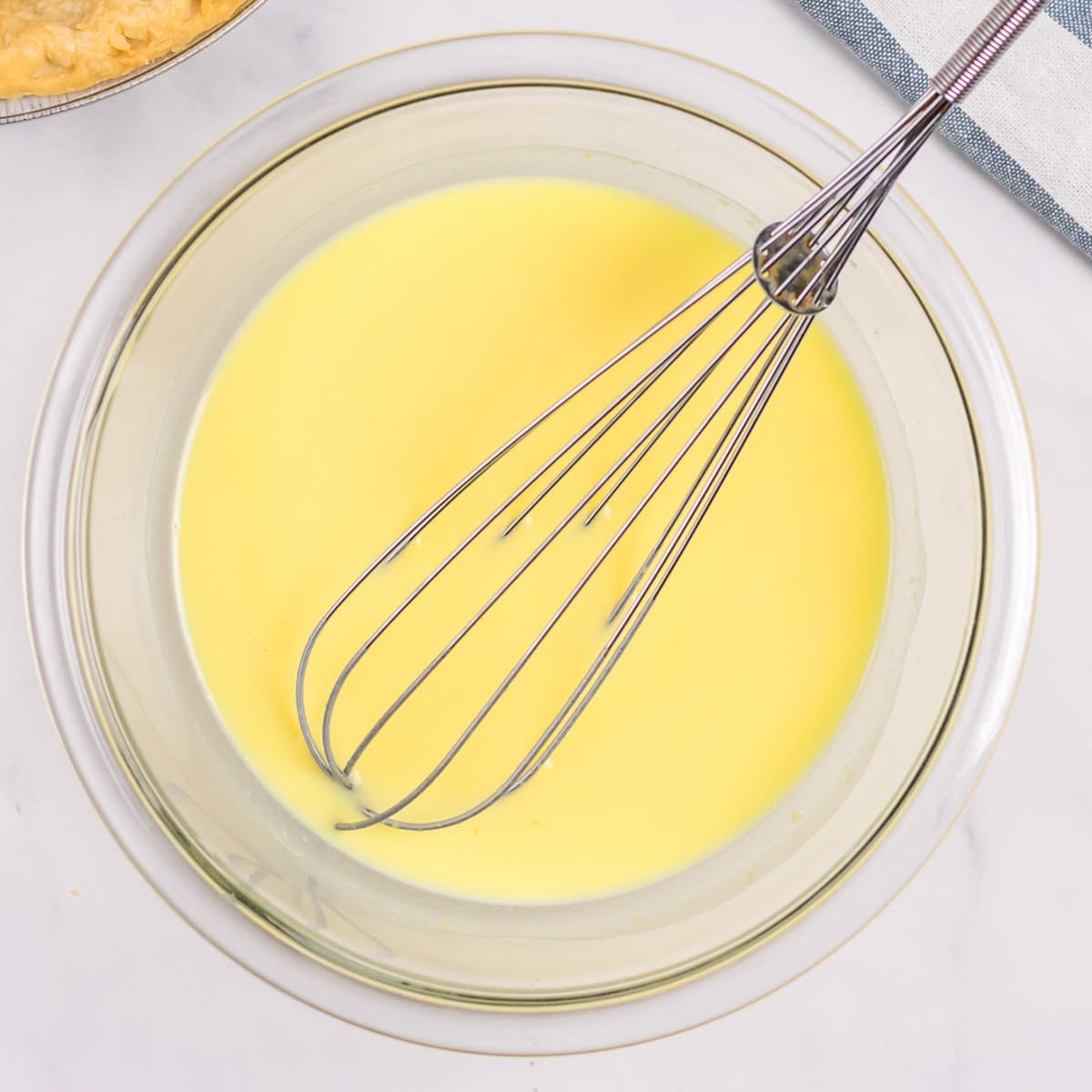vanilla pudding in a glass bowl with a whisk