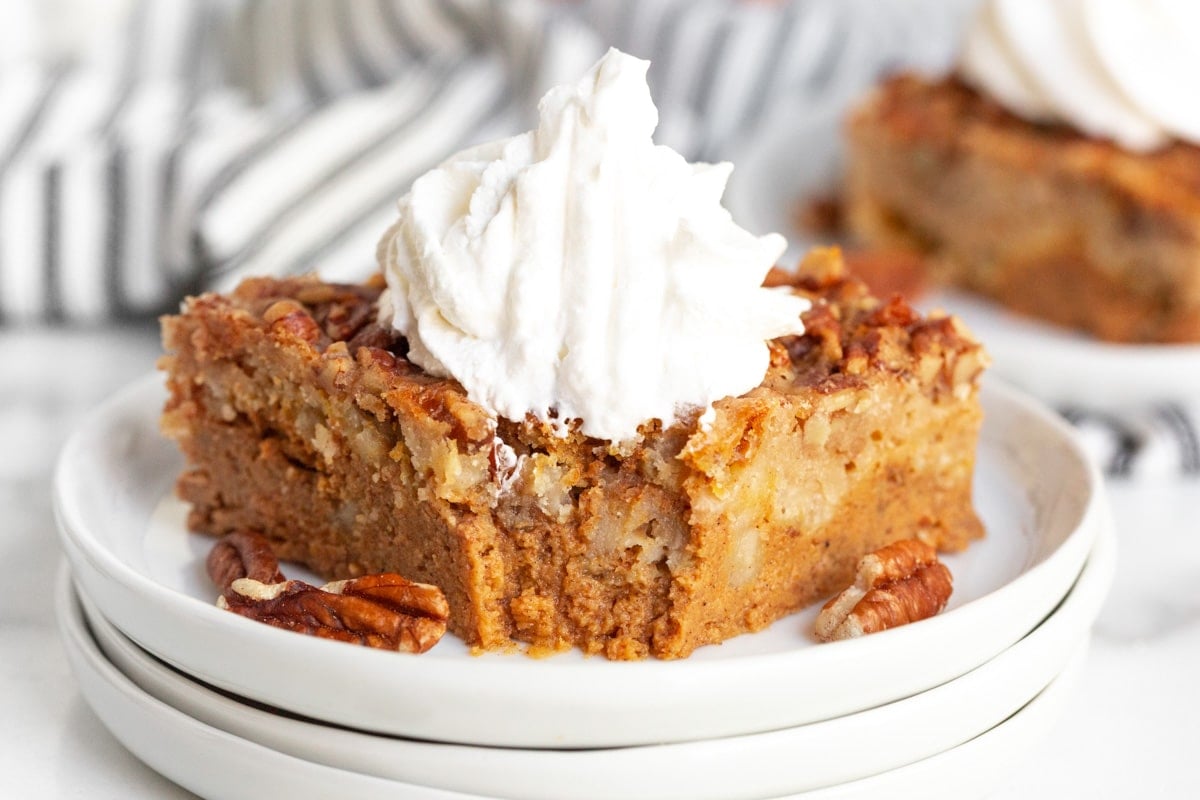 a piece of pumpkin pecan dump cake with whipped cream with a bite out