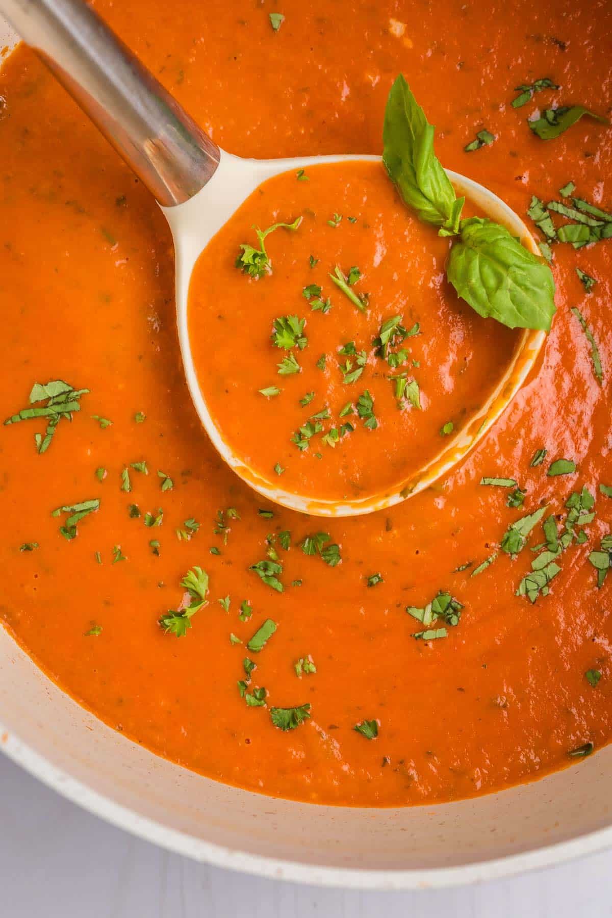 overhead view of tomato bisque soup in a ladle