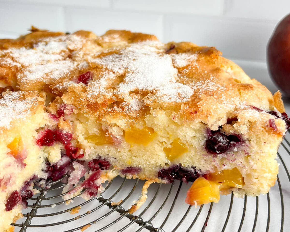 closeup of peach blueberry cake on a wire rack