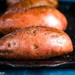 a raw sweet potato on a baking sheet
