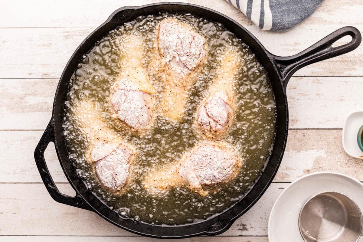 chicken legs in a skillet with oil