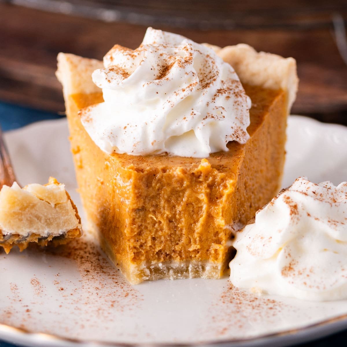 a piece of pumpkin pie on a plate with one bite out
