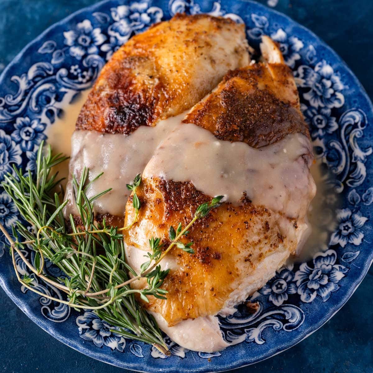 two chicken breasts with gravy on a table