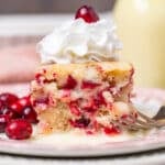 a piece of white cake with cranberries and whipped cream on top