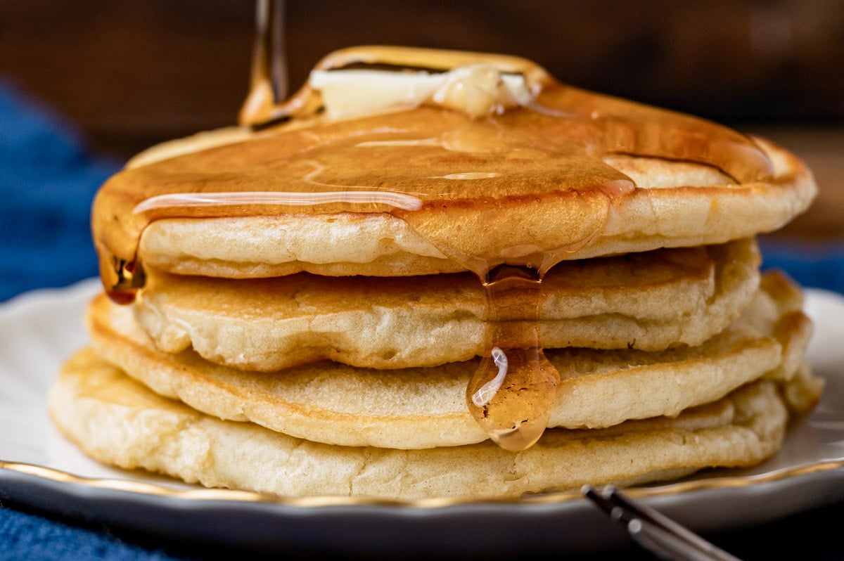 a stack of 4 homemade pancakes with syrup dripping