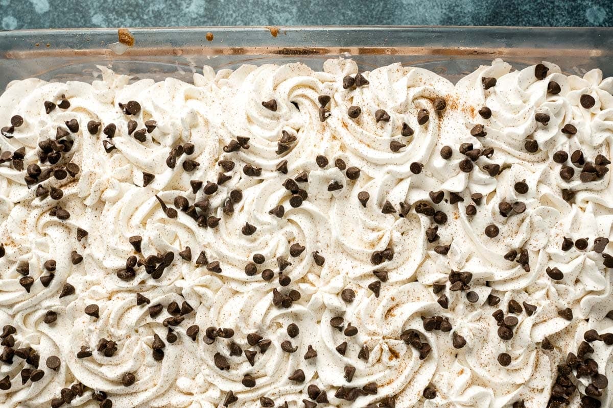 swirls of white frosting and chocolate chips in a baking pan