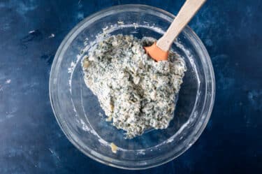 cheesy spinach artichoke mixture in a glass bowl