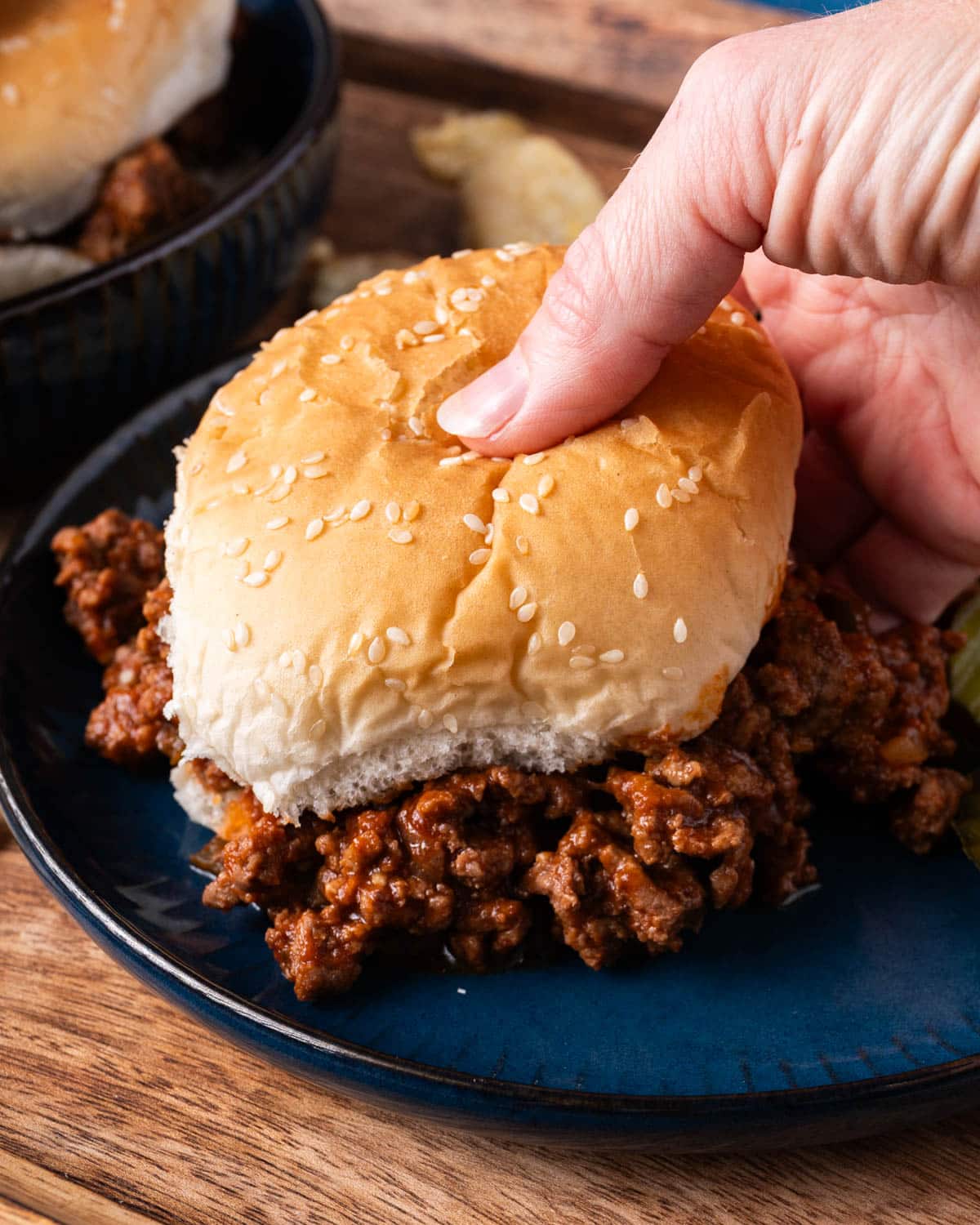 a hand picking up a sloppy joe sandwich