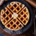 a plate with a sourdough waffle on it with butter and syrup