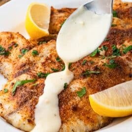 spooning lemon dijon sauce over tilapia