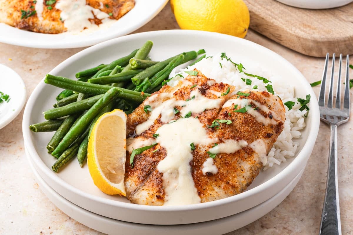 a plate of tilapia with green beans and lemon dijon sauce