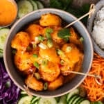 a bowl of bang bang shrimp in a bowl with veggies around it
