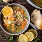 a bowl of chicken soup with lemon and rice on a table