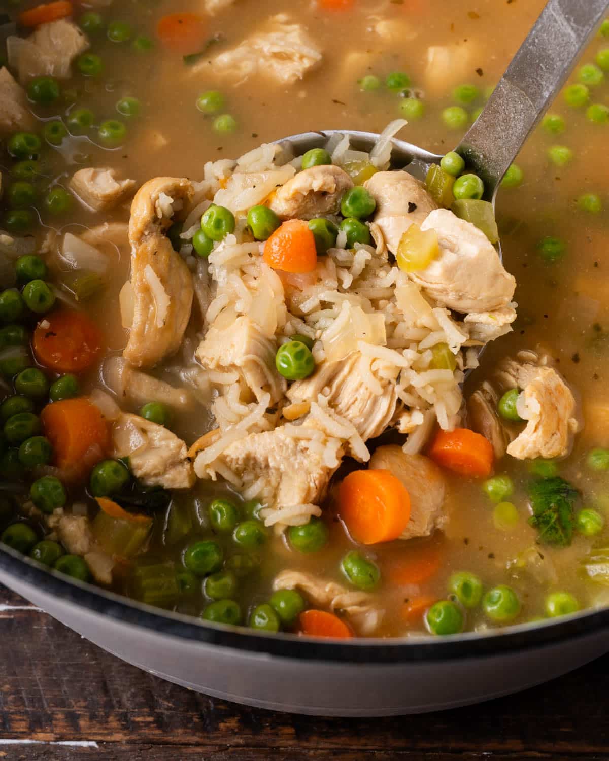a ladle of lemon chicken rice soup in a pot