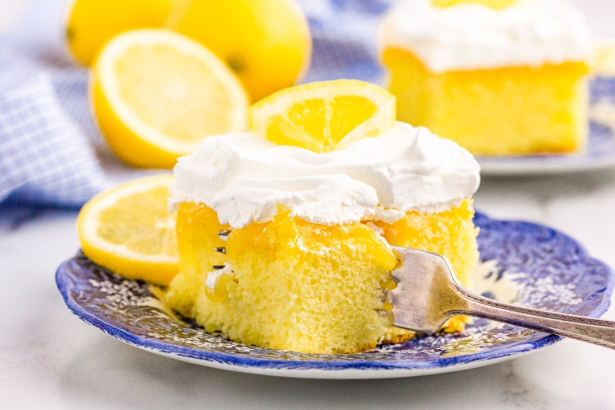 a slice of lemon poke cake on a plate with a fork