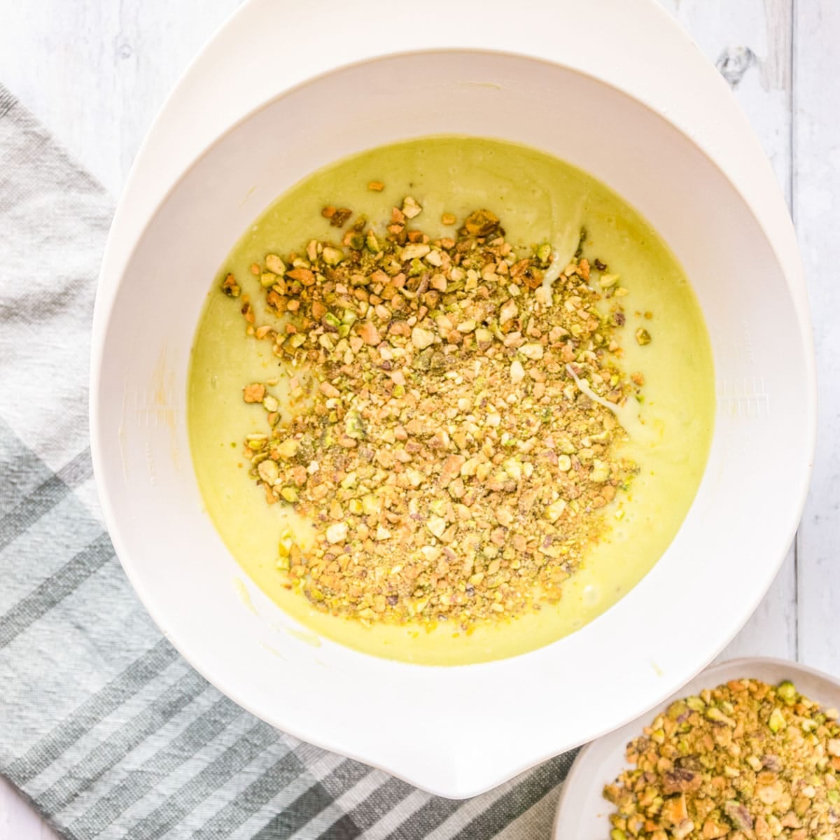 pistachios over cake batter in a bowl