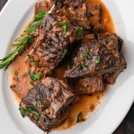slow cooker short ribs on a plate with fresh herbs