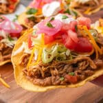 a hand holding a tostada with beans and chicken