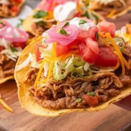 a hand holding a tostada with beans and chicken