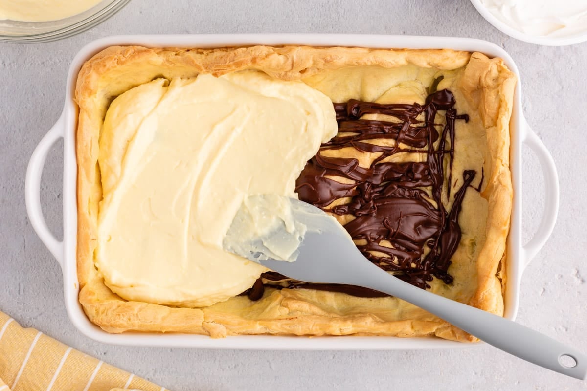 a spatula spreading pudding over a crust with chocolate