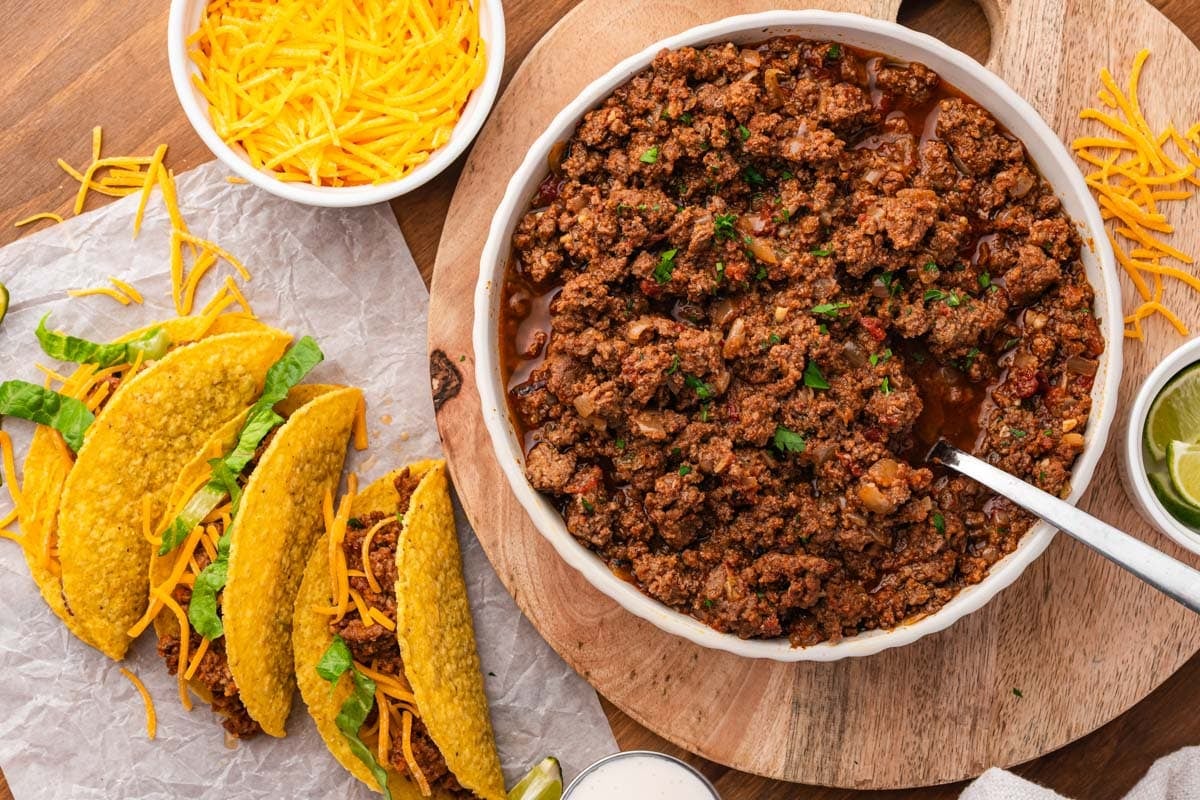 taco meat and 3 tacos with cheese on a table