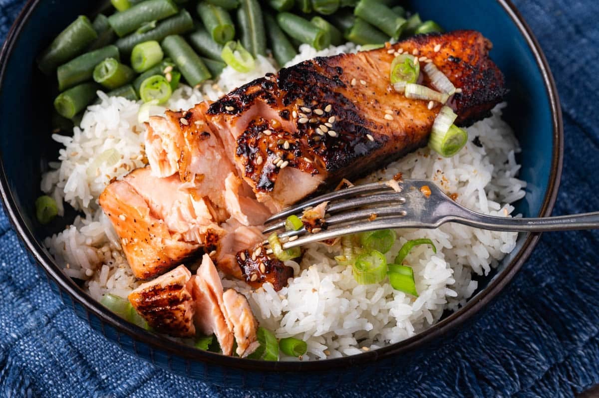 a fork flaking salmon on a bed of rice