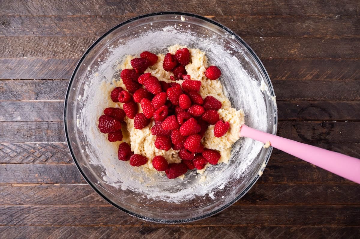 raspberries over cake batter in a bowl