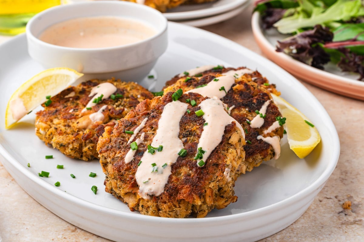 3 salmon patties on a plate with spicy mayo sauce