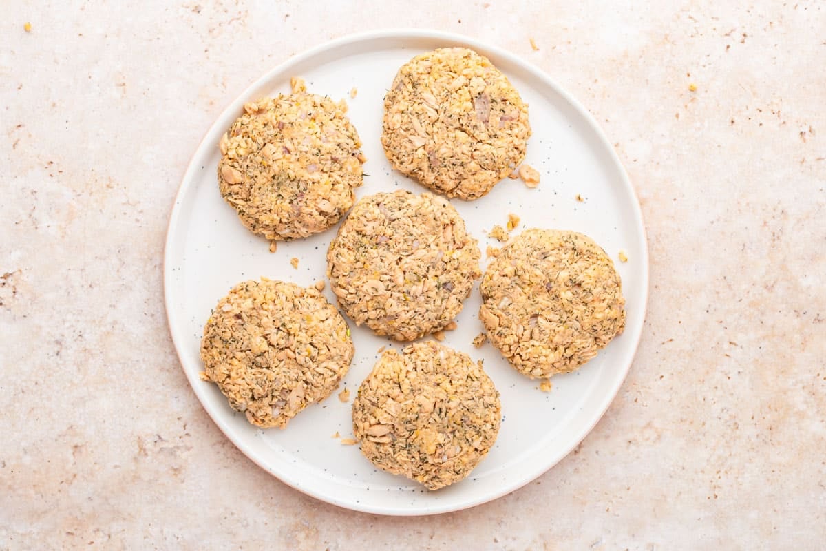 uncooked salmon cakes resting on a white plate