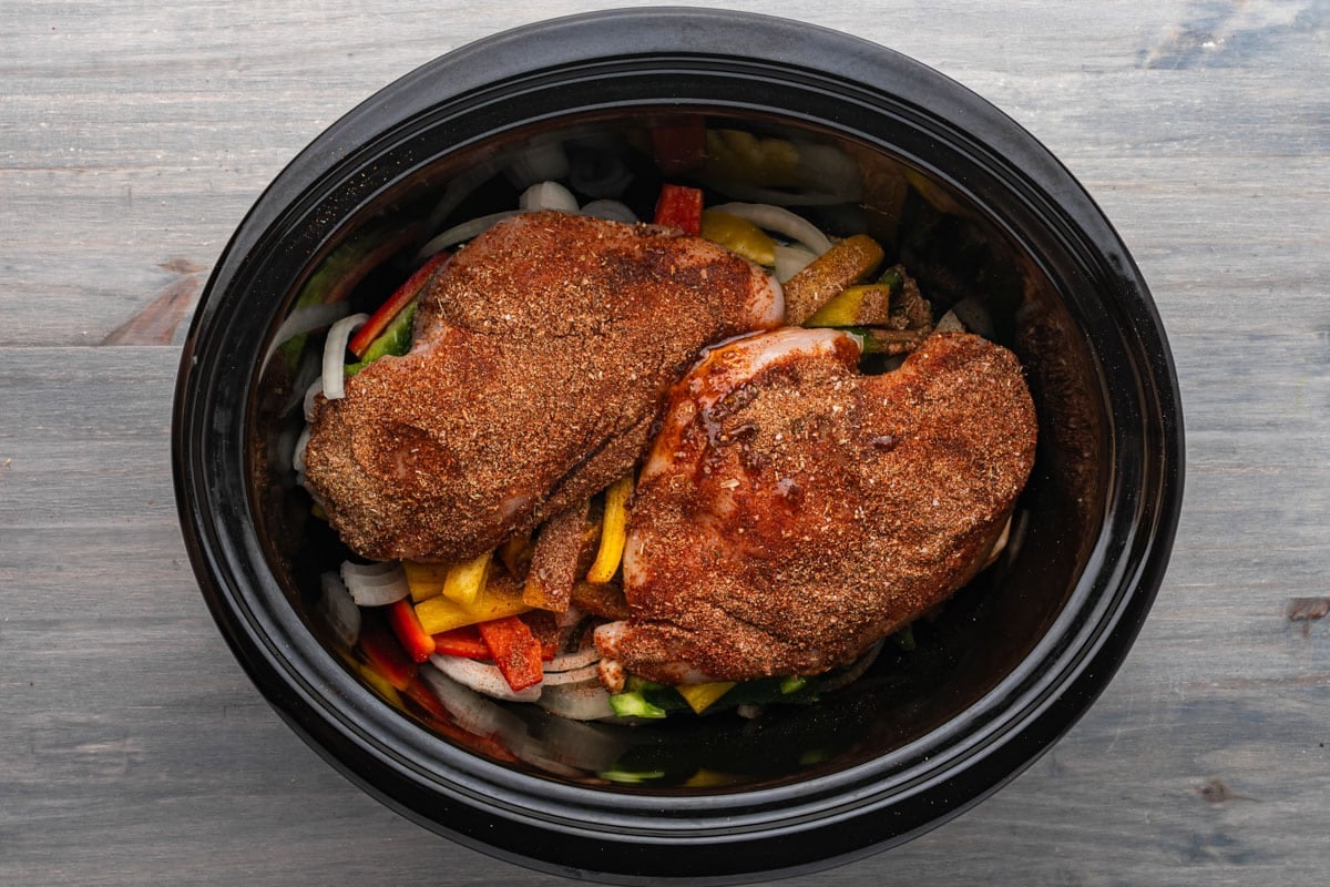 chicken breasts over pepper and onions in a crockpot
