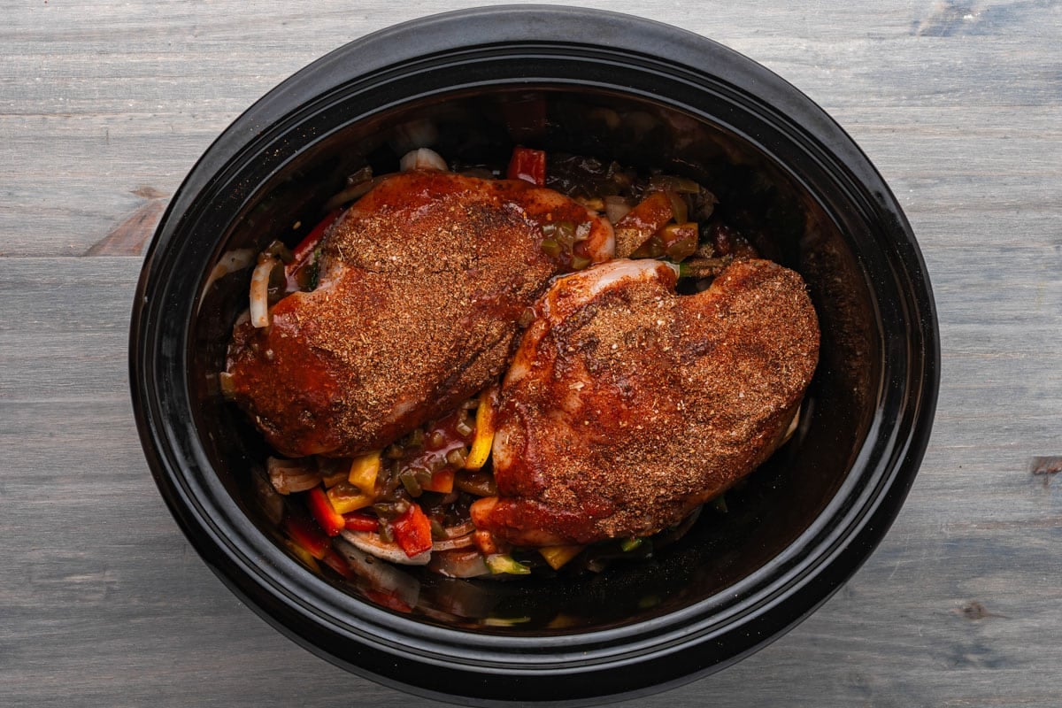 uncooked chicken and onions in a crockpot