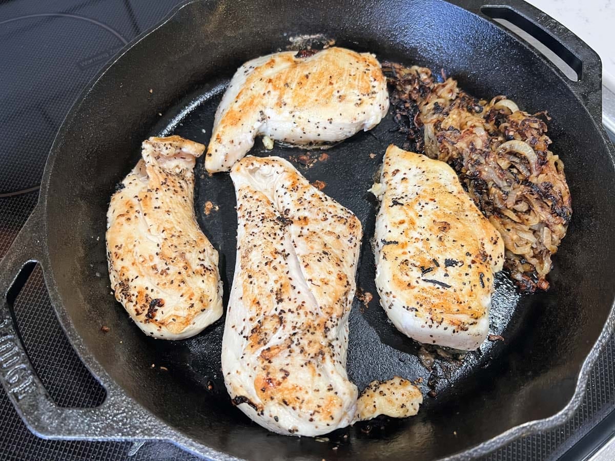 jammy onions and seared chicken in a skillet