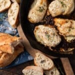 overhead view of a skillet of french onion chicken and bread