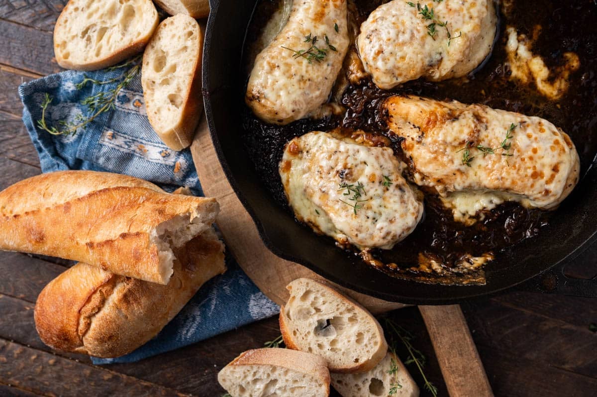 overhead view of a skillet of french onion chicken and bread