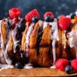 a loaf of berry pull apart bread with fresh berries and glaze