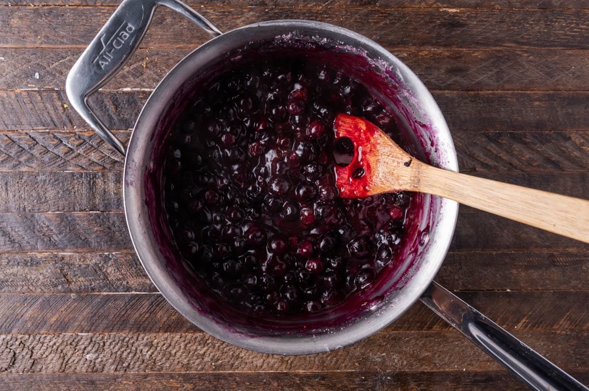 blueberry filling in a saucepan with a wooden spoon