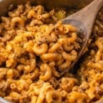 a spoonful of elbow macaroni and cheesy hamburger in a skillet