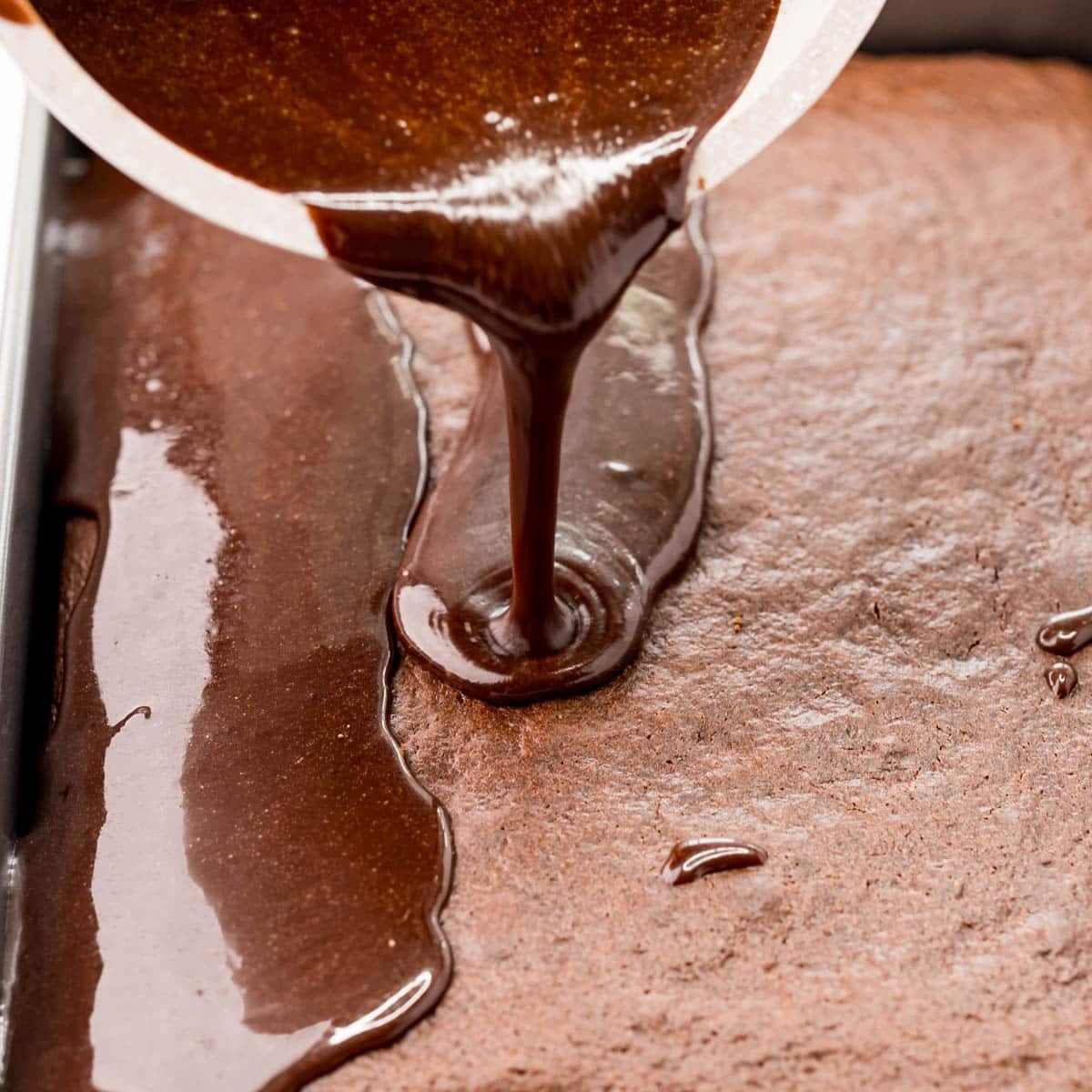 drizzling chocolate glaze over a cake