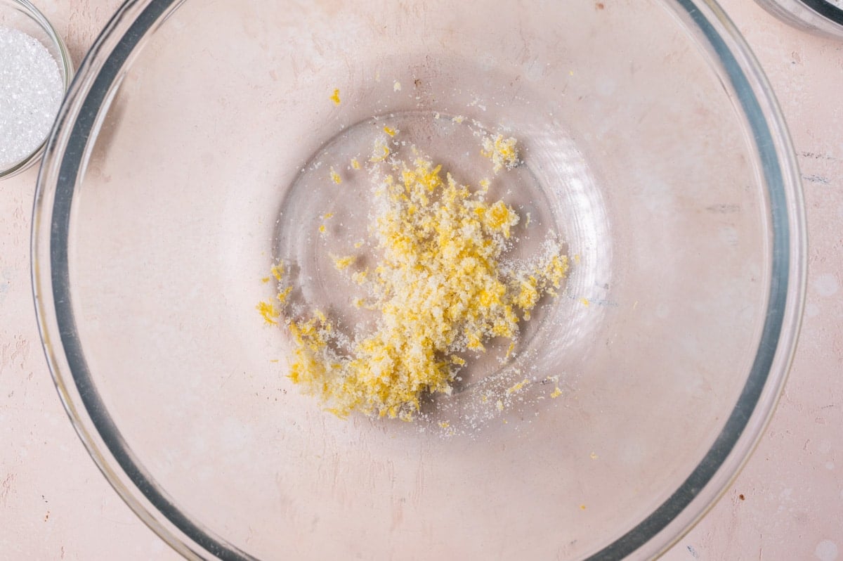 lemon zest pressed into sugar in a glass bowl