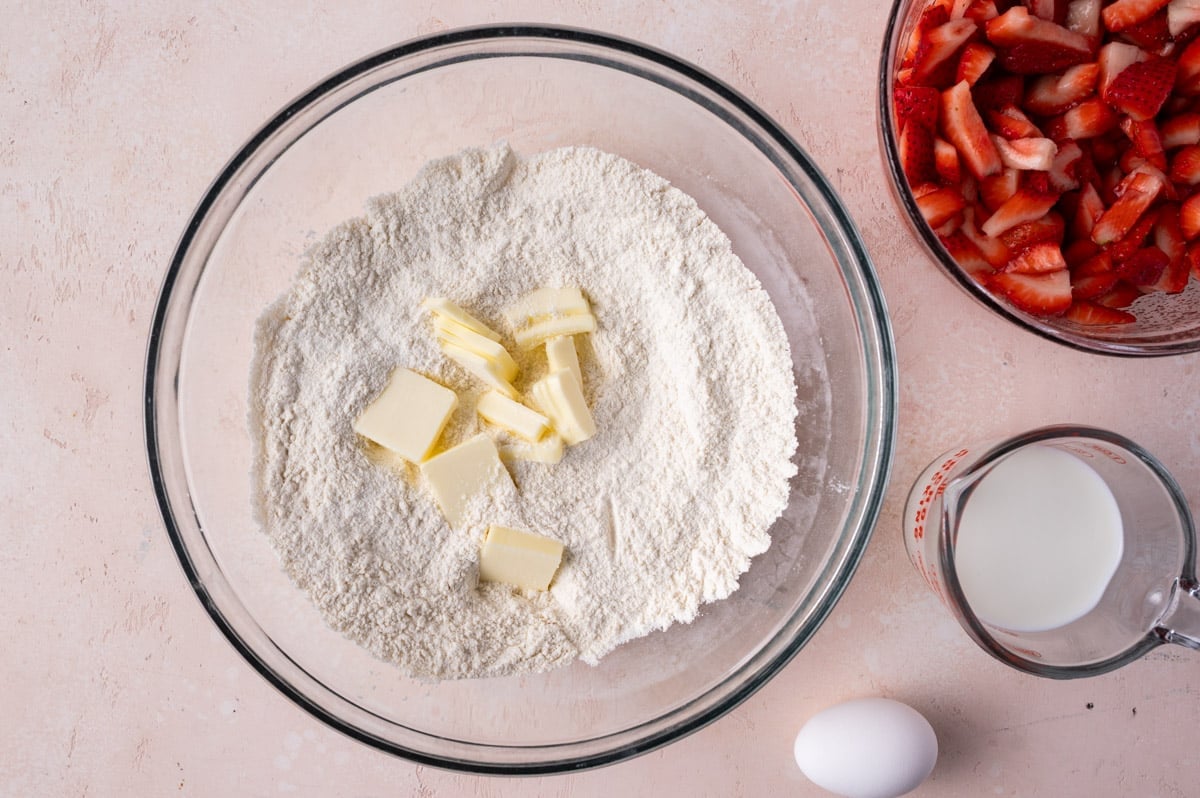 cubed butter over flour in a mixing bowl on a table