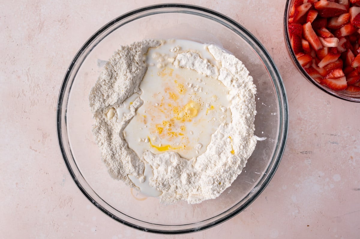 milk and egg poured over dry ingredients in a mixing bowl