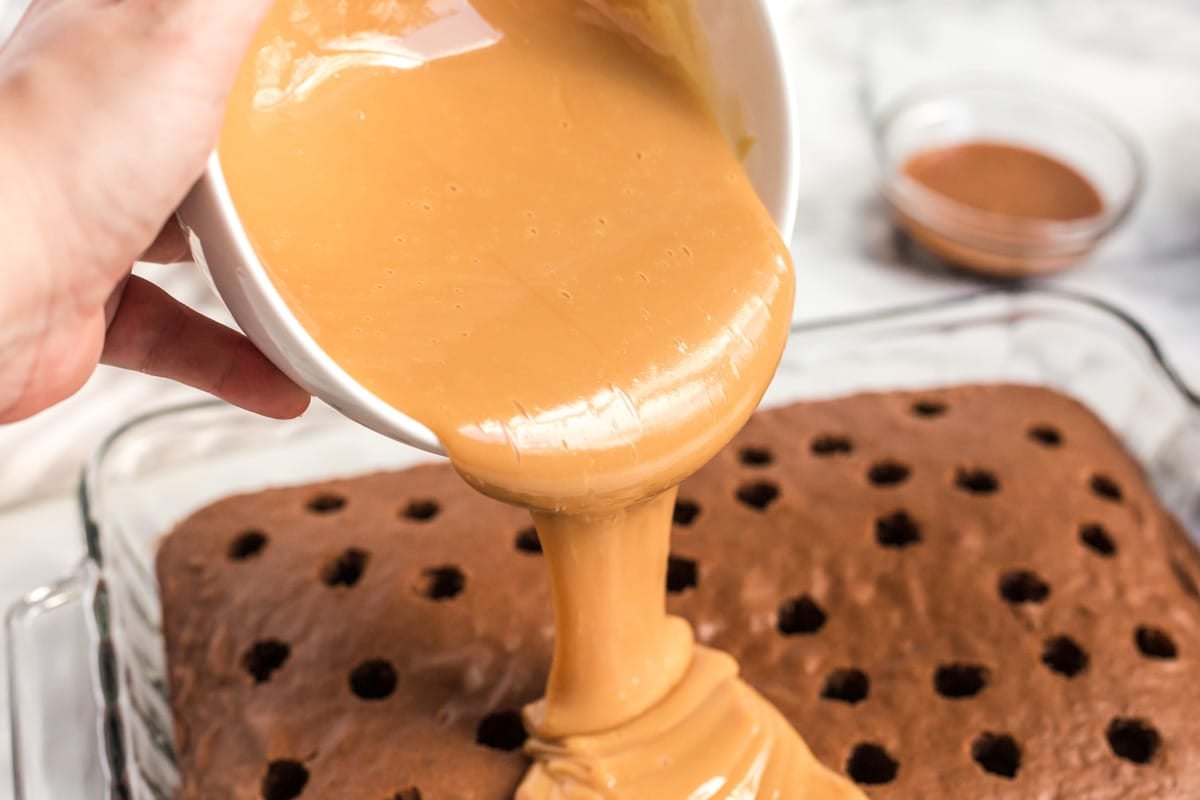 caramel pouring over a chocolate poke cake