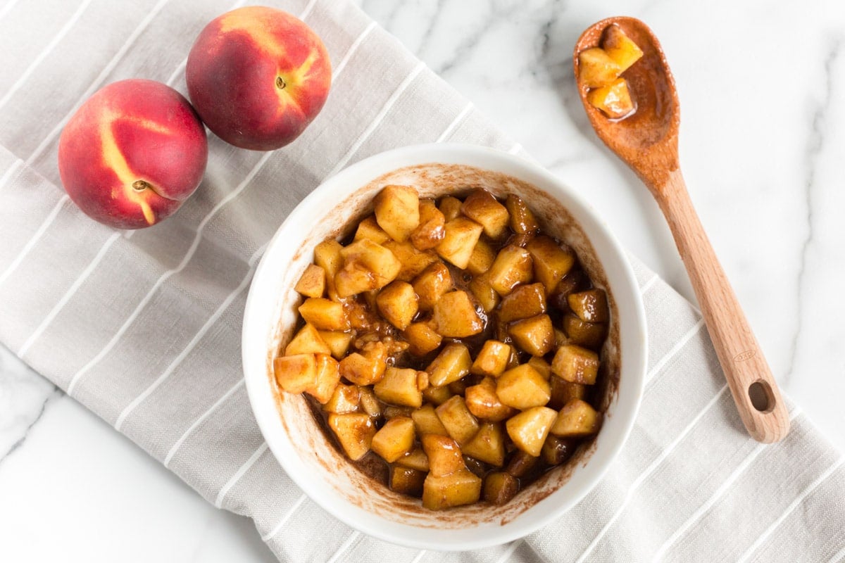 cinnamon sugar over peaches in a bowl