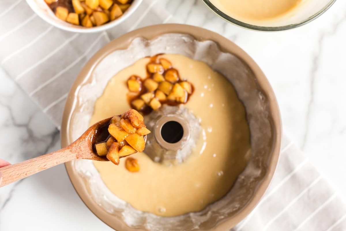 layering cinnamon peaches over cake batter in a bundt pan