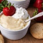 two bowls of vanilla pudding on a table with a spoon