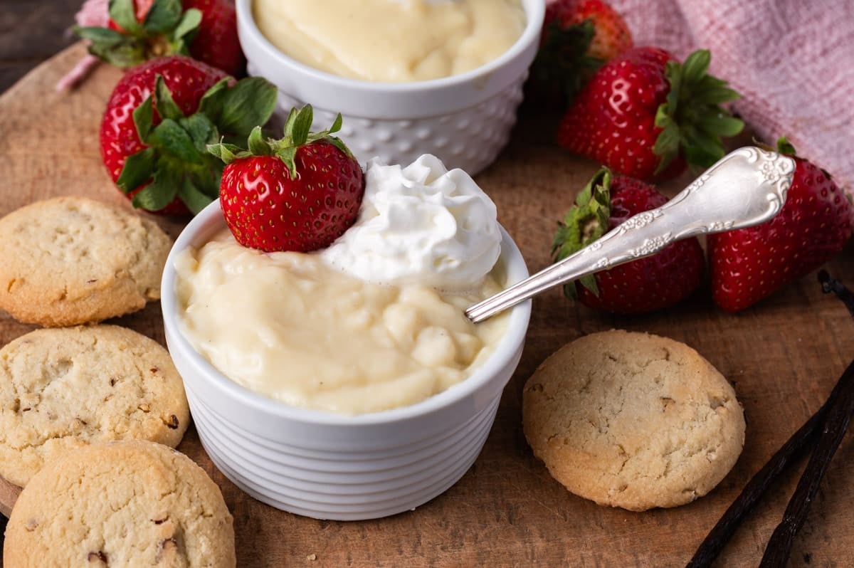 two bowls of vanilla pudding on a table with a spoon