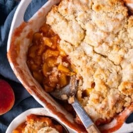 peach cobbler in a pan with one serving out