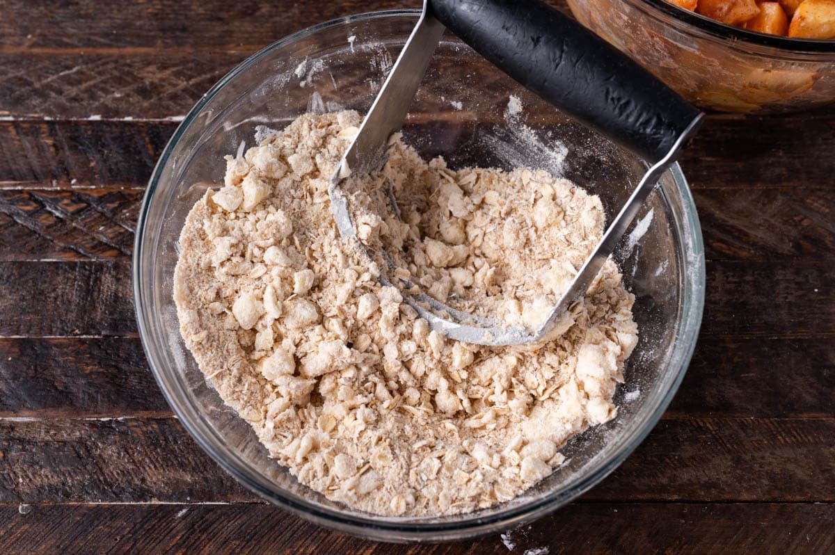 peach streusel in a bowl with a pastry cutter
